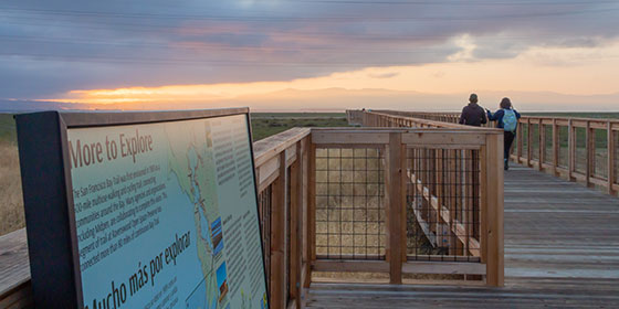 two hikers on the wooden boardwalk at Ravenswood Open Space Preserve