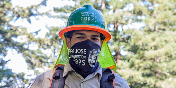 a young man wearing a hard hat and COVID mask
