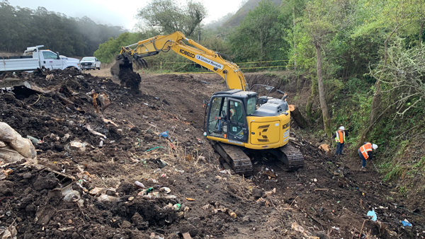 bulldozer cleaning garbage off a hillside