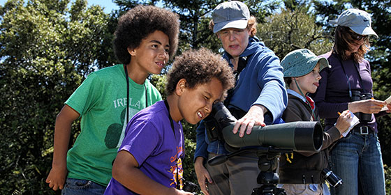 two boys looking through a scope looking for birds