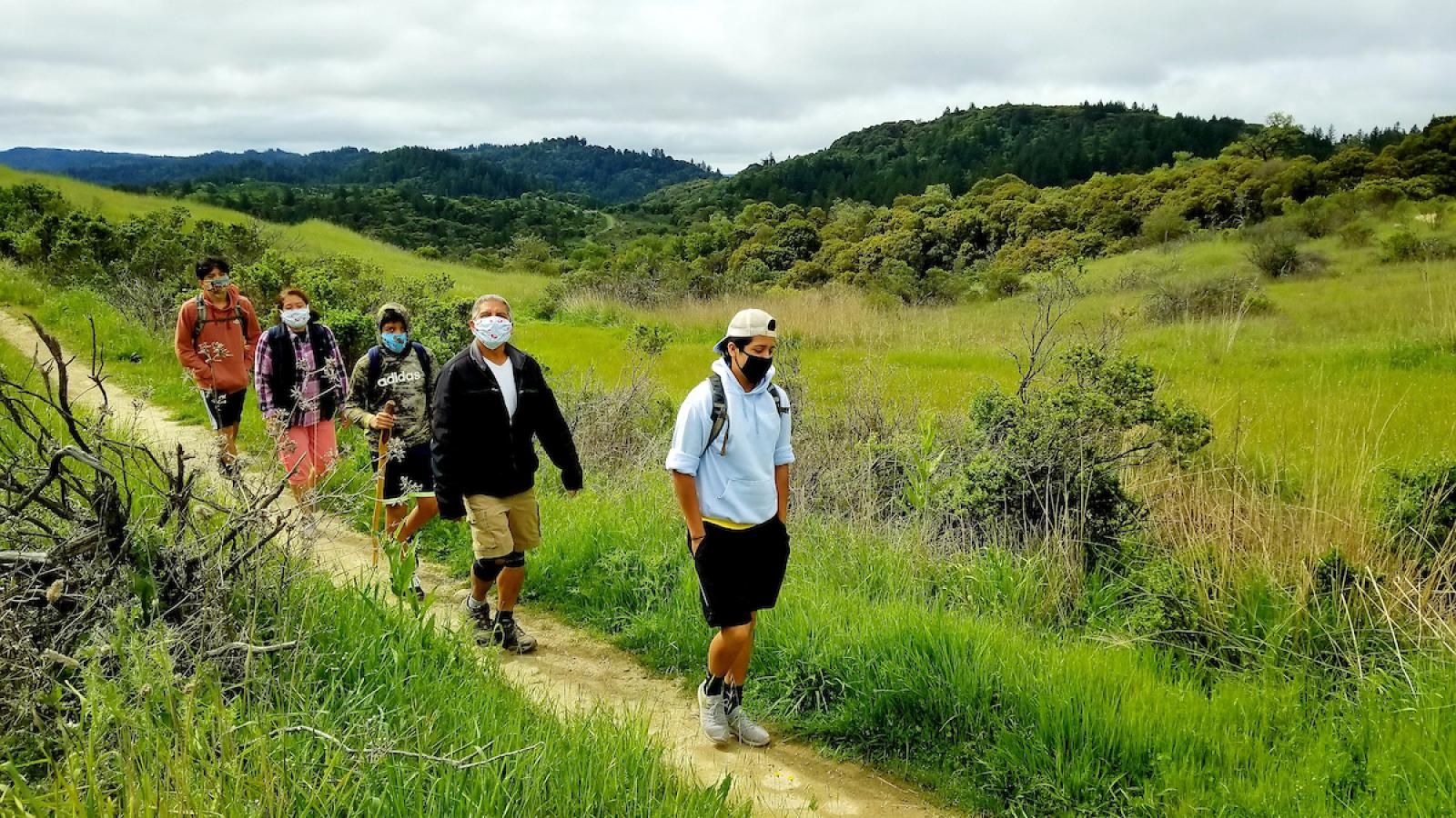 a family hiking on a trail wearing face coverings