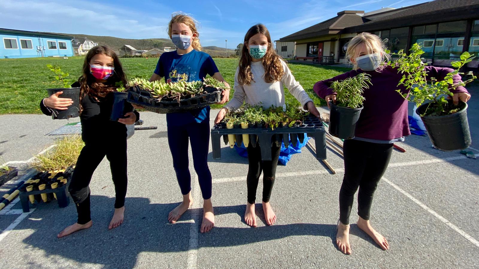 girls holding potted plants