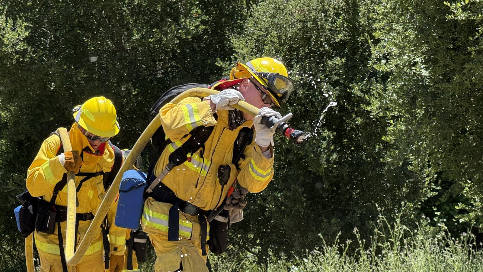 Midpen staff in fire gear carrying hose