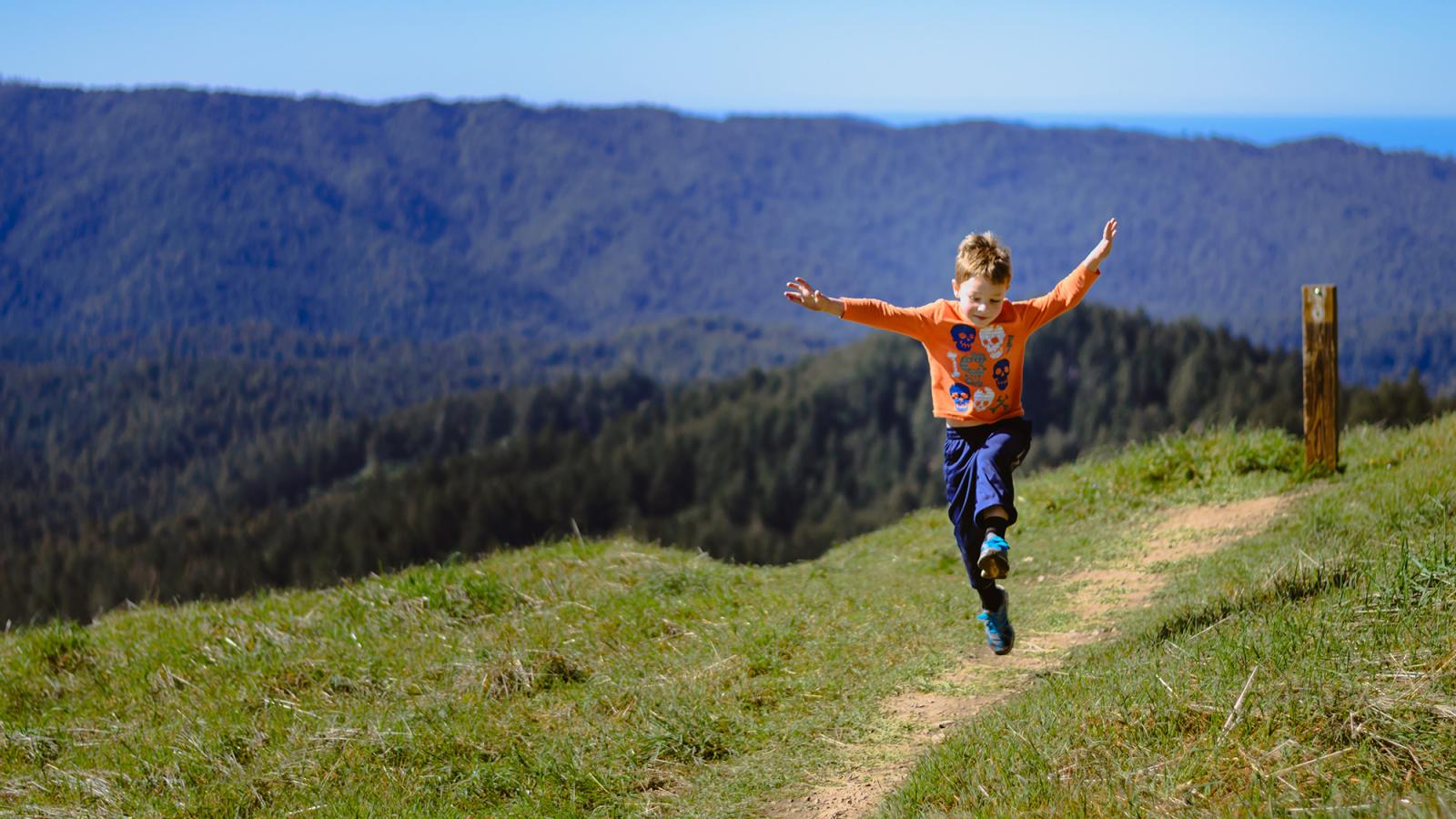 a boy skipping along a trail