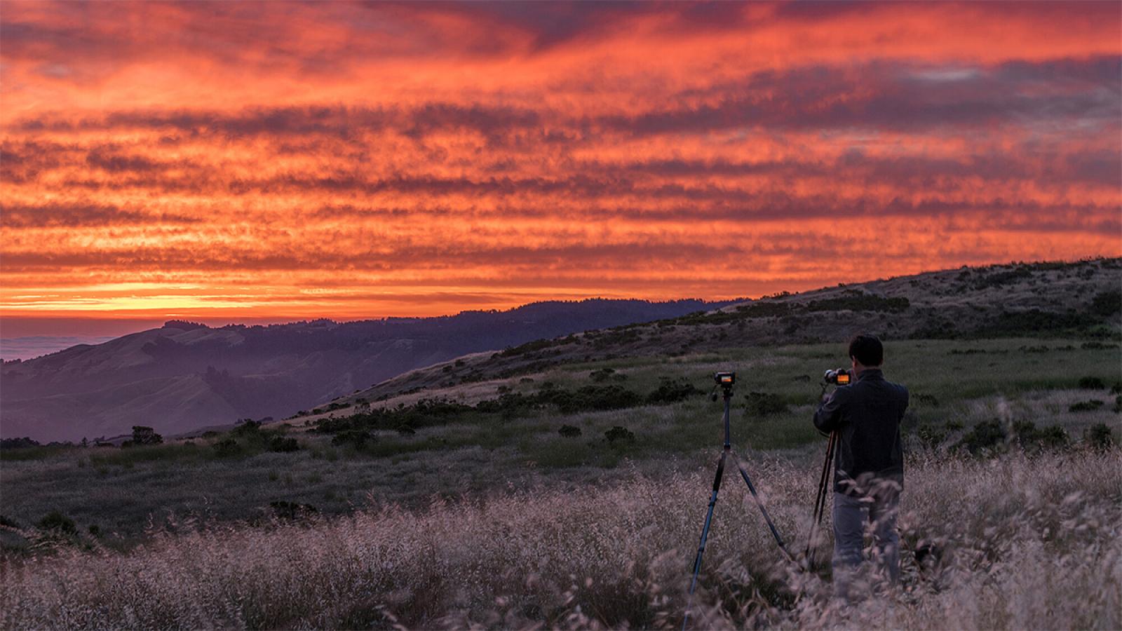 a man taking a photo of the sunset