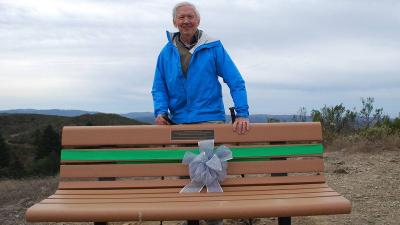 Herb Grench stands with a bench dedicated to him at Windy Hill Open Space Preserve