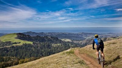 Mountain bicyclist on the Bay Area Ridge Trail in Midpen's Russian Ridge Preserve with a view of Mindego Hill and the San Mateo County Coast. (Karl Gohl) 