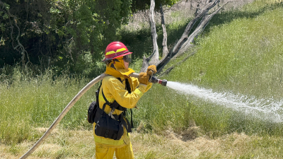 Midpen staff in fire gear spraying hose