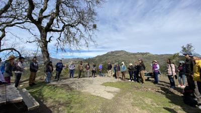 Group stands in circle outdoors for a discussion