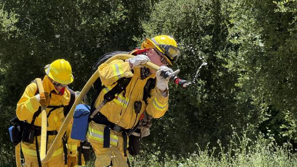 Midpen staff in fire gear carrying hose