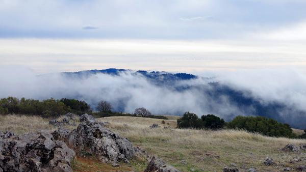 fog on the ridgeline above a rocky plain