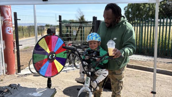A father holds a child steady on a bike