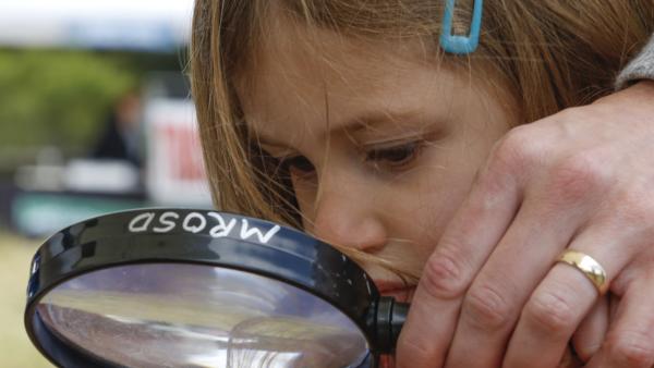 Girl looking through a magnifying glass.