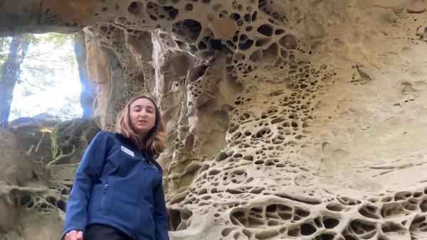 a woman standing in front of tafoni rock