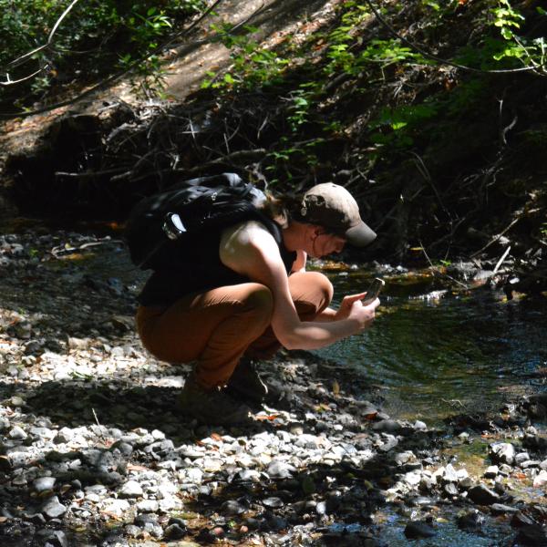 An intern takes a photo of a creek